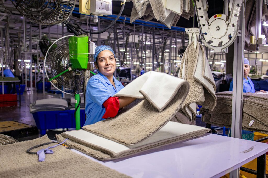 Cheerful female worker processing textiles in a busy garment factory.