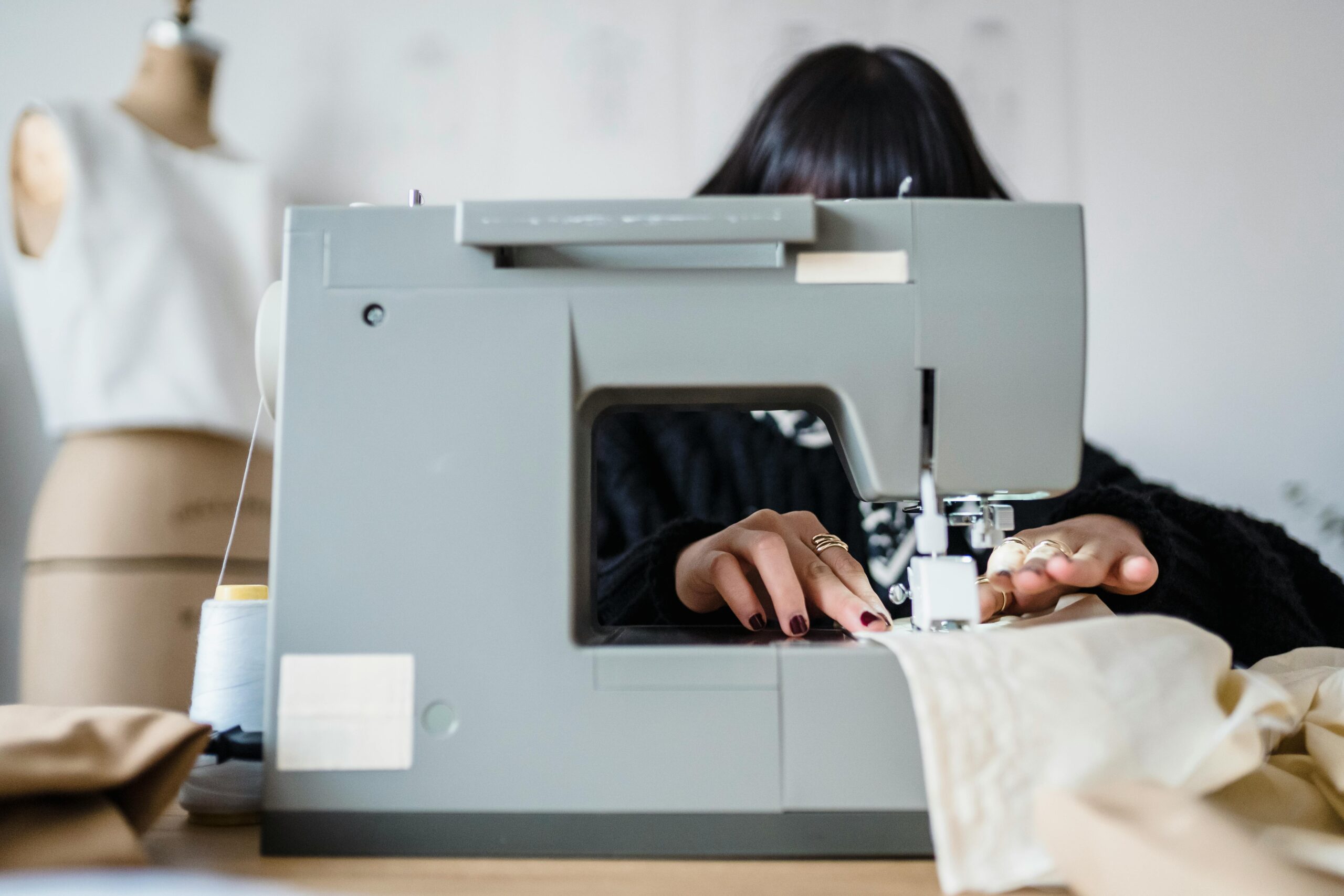 A woman sewing fabric on a machine in a creative workshop space.