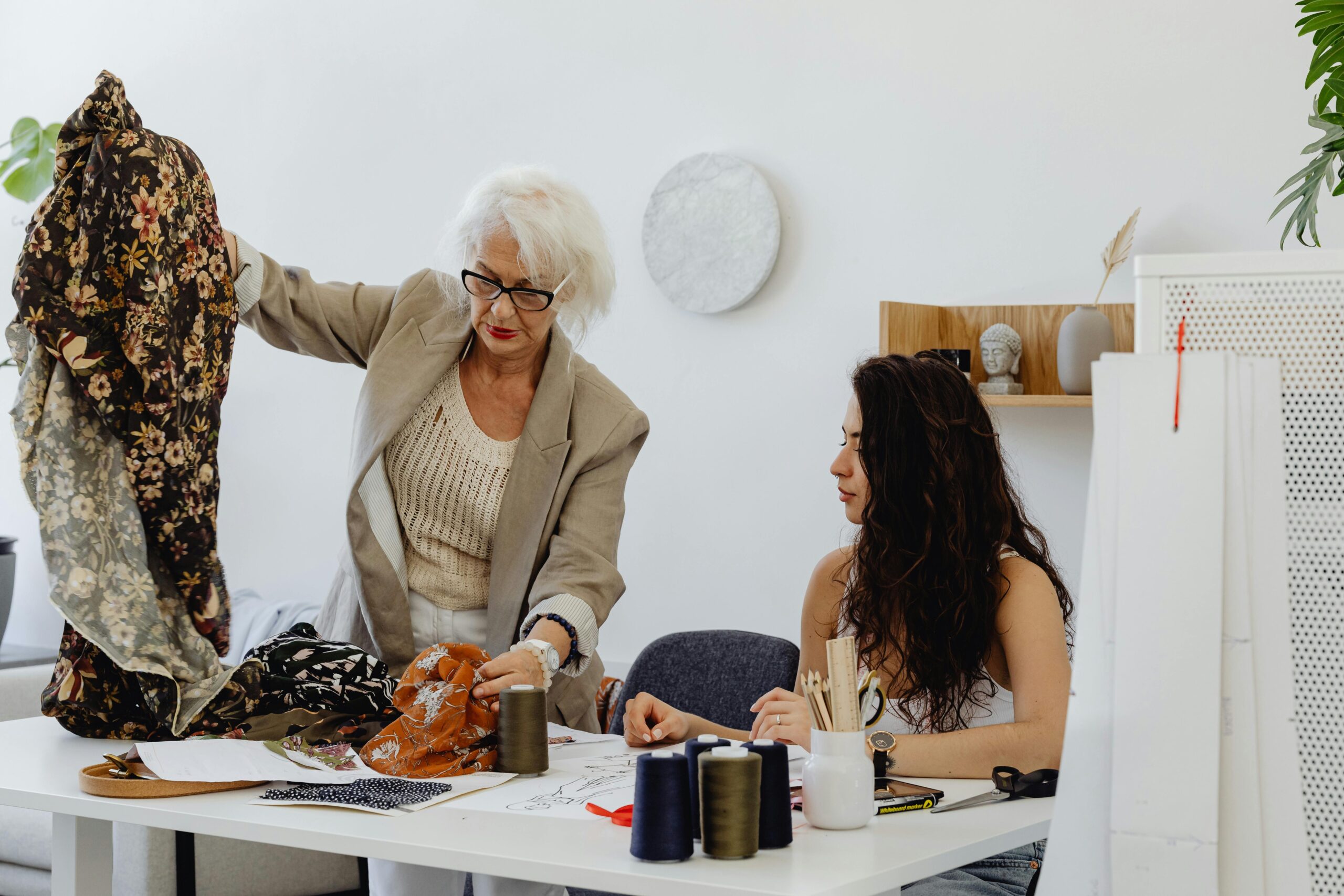 Two women in a fashion studio discussing fabrics and designs for a project.